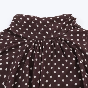 Detailansicht der dunkelbraunen Polka-Dot-Bluse mit plissiertem Stehkragen am Ausschnitt