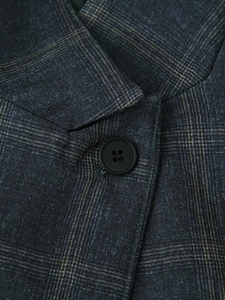 Close-up of the grey plaid suit fabric with a black button and detailed woven texture