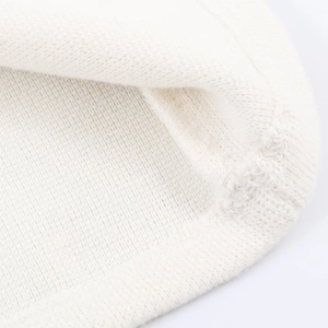 Close-up of fine white knitted fabric texture and detailed hem stitching on the top