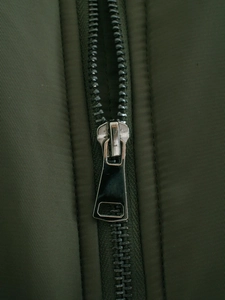 Gros plan d'une fermeture éclair en métal sur un blouson aviateur vert olive