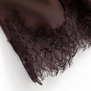 Detail of dark chocolate satin fabric featuring delicate eyelash lace trim and stitching
