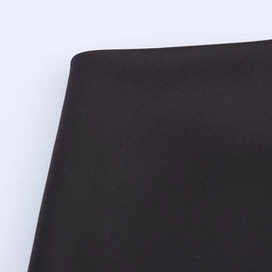 Macro shot of dark satin fabric texture and precise hem detail on a halter mini dress