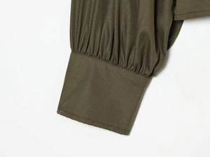 Close-up of olive green poplin shirt cuffs featuring detailed pleating and stitching