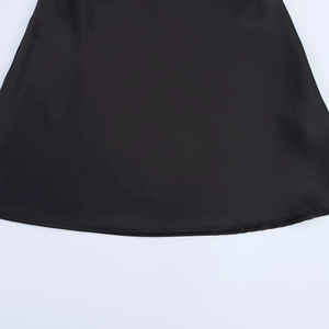 Close-up of the smooth black satin dress hem with precise stitching and refined texture