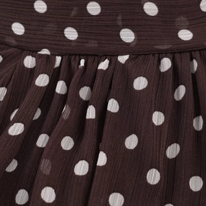 Nahaufnahme von plissiertem Chiffonstoff mit weißen Punkten auf brauner Bluse