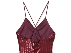 Detail of burgundy sequin dress showing cross back straps and shimmering fabric texture