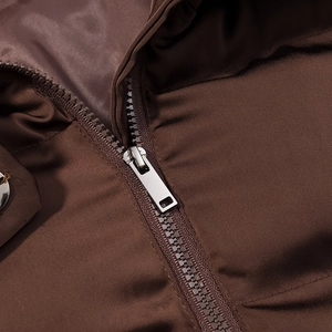 Close-up of a silver metal zipper on a dark brown street style cropped puffer jacket