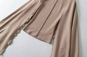 Detail of khaki two-piece top showing structural vertical stitching and wide drape sleeves