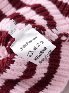 Détail de l'étiquette d'entretien 100 % polyester sur le pull rayé rose et rouge