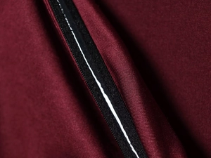 Detailed macro view of high-quality waterproof black zipper on burgundy twill fabric shirt