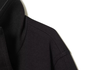 Detail shot of black wool blend fabric texture and stitching on the collar and shoulder