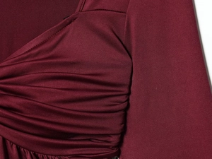Macro detail of wine red V-neck top featuring elegant pleated layers and fabric texture