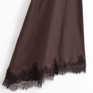 Detail shot of deep brown satin fabric with delicate black eyelash lace trim on the hem