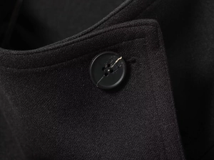 Close-up of classic black four-hole button on high-quality wool coat fabric texture