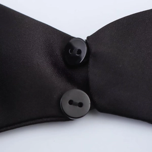 Detailed macro view of black satin fabric with two glossy buttons on backless mini dress
