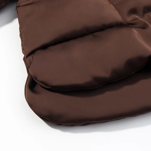Detailed view of horizontal quilting and glossy fabric on dark brown cropped puffer jacket
