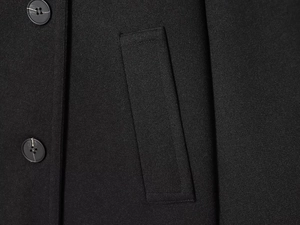 Close-up detail of black jacket featuring two round buttons and a rectangular flap pocket