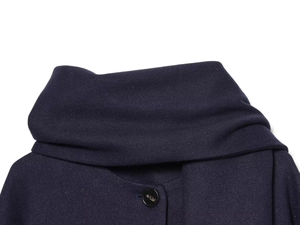 Macro detail of the dark blue wool blend coat collar with a sleek resin button and stitching