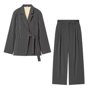 Detail of dark gray pinstripe suit set showing belted waist blazer and wide-leg trousers