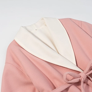 Détail du col d'un manteau en laine rose avec étiquette taille S et doublure beige