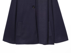 Detail of navy wool blend coat featuring symmetric flat pockets and premium button
