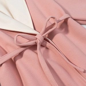 Détail du manteau en laine rose et blanc montrant la ceinture et la texture douce
