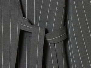 Detailed close-up of dark grey pinstripe fabric with a matching waist belt tie detail