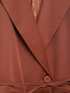 Detailansicht eines ziegelroten Blazers mit Reverskragen, passendem Knopf und Kordelzug