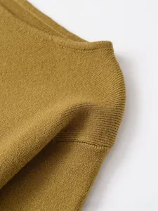 Dettaglio della maglia giallo senape che mostra la trama a costine e il morbido tessuto