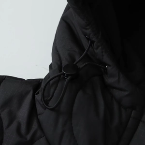 Detail shot of black quilted jacket showing adjustable drawstring and ripstop fabric