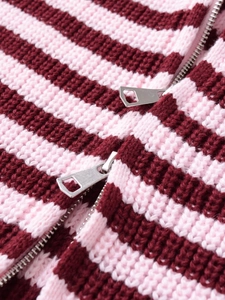 Close-up of pink and burgundy striped knit sweater with dual silver metal zippers