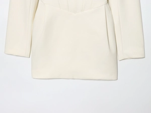 Close-up of structured waist pleats and V-shape stitching on ivory blazer dress