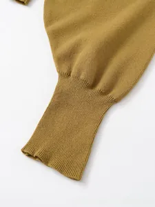 Dettaglio macro della maglia giallo zenzero con polsini a costine e cuciture fitte