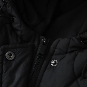 Detail view of quilted black puffer jacket featuring a metal zipper and silver snap buttons