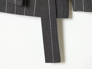 Detailed close-up of dark grey pinstripe suit fabric showing fine texture and wide belt