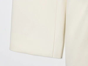 Detailed macro view of cream white woven fabric texture and stitching on blazer dress