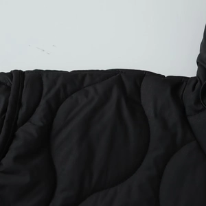 Detailed close-up of waterproof quilted fabric and wave stitching pattern on black winter coat