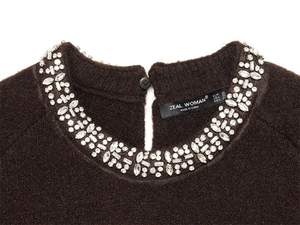 Detail of knit sweater neckline with sparkling rhinestones and teardrop button closure