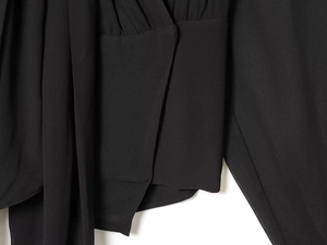 Detail of elegant black wrap blouse featuring pleated waist and matching chiffon ribbon tie