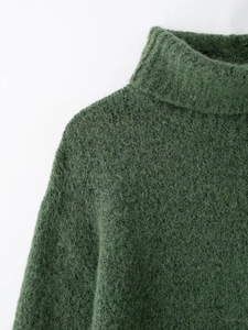 Dettaglio ravvicinato di maglia a collo alto verde scuro con morbida trama in mohair