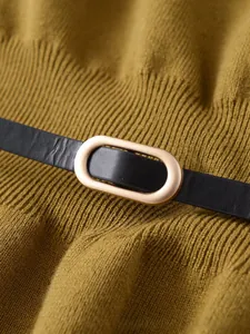 Dettaglio del tessuto in maglia giallo zenzero con cintura in pelle nera e fibbia oro
