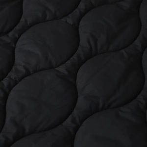 Macro detail of black onion-quilted ripstop fabric on waterproof padded jacket