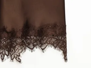 Detailaufnahme von braunem Satinstoff mit zarter Wimpernspitze am Saum des Kleides