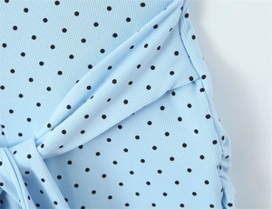 Close-up of light blue polka dot ribbed jumpsuit fabric with a delicate tie-knot detail