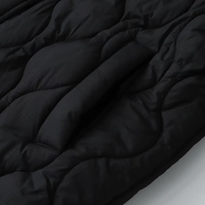 Detail of onion-quilted ripstop texture and hidden side pocket on black puffer coat
