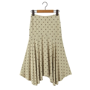 Détail d'une jupe midi à pois taille haute beige avec un drapé fluide et asymétrique