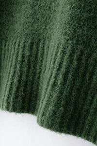 Dettaglio maglione in maglia mohair verde scuro con morbida trama e polsini a costine