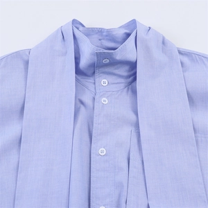 Detail of light blue stand collar shirt with bow tie and high-quality fabric texture