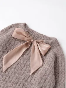 Close-up of fluffy mauve knit sweater texture with decorative silk ribbon bow detail