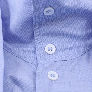 Detail of light blue button-down shirt featuring a sharp collar and neat stitching